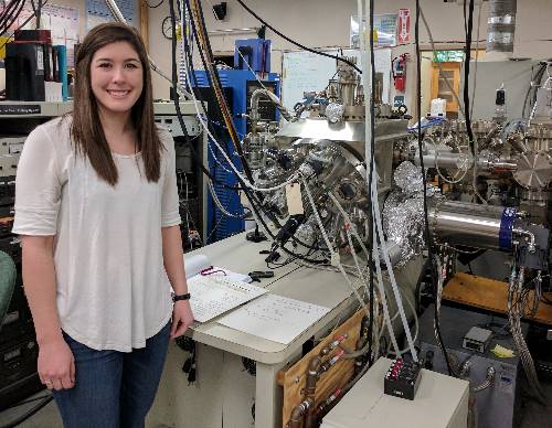 Graduate student in front of equipment 